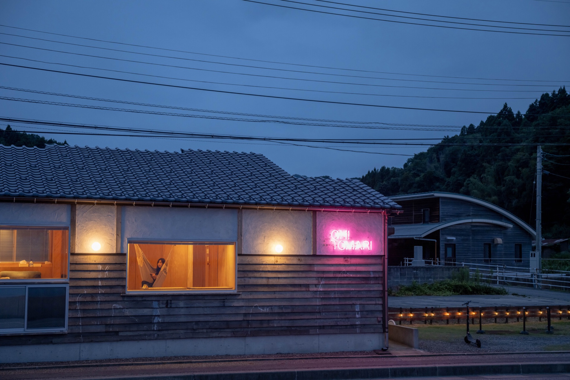 夜のOH!TOMARI。窓の明かりとネオンサイン、その向こうに海